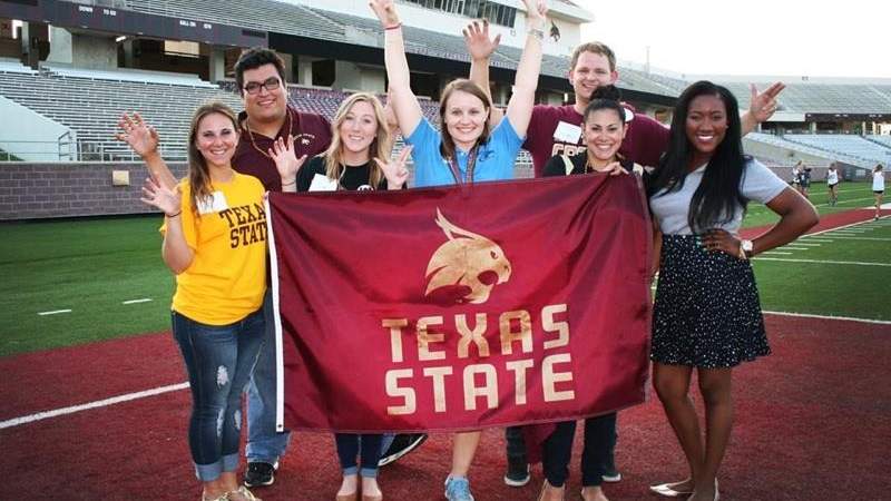 SAHE students standing next to a Texas State flag