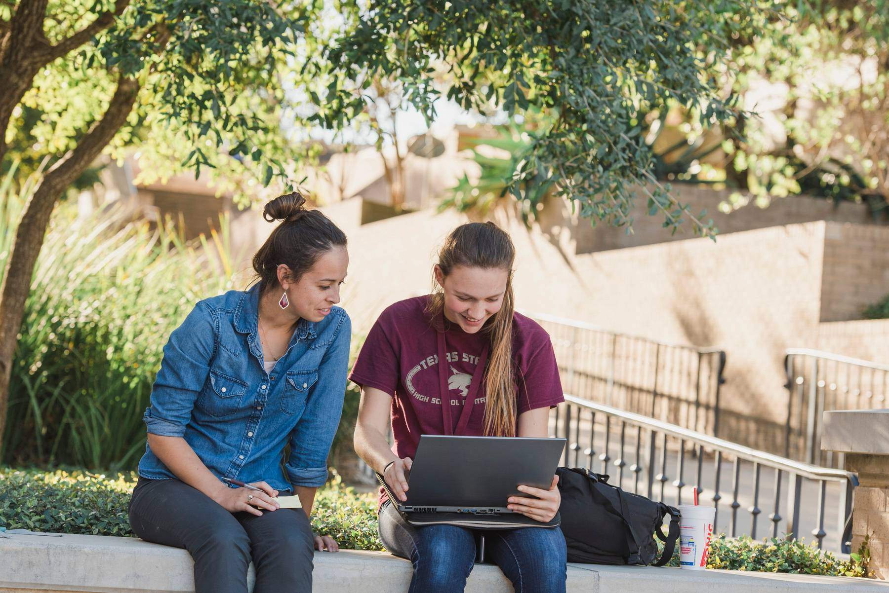 Two students sitting outside working on a laptop