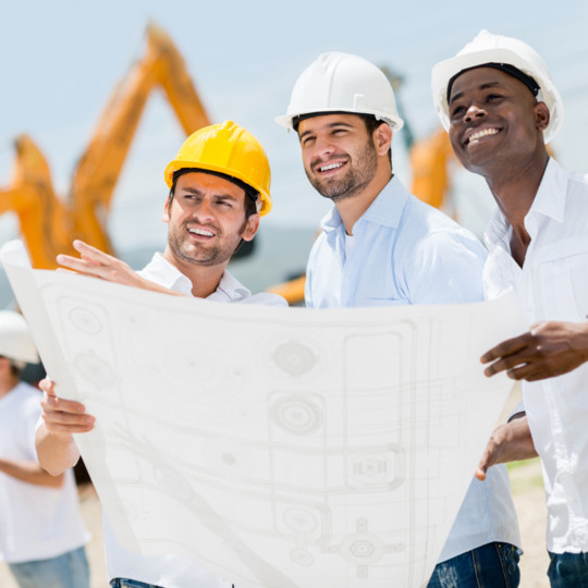 Picture of three construction men workers reviewing a blueprint of an onsite construction project.