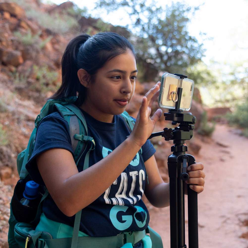 A student looks at her phone on a tripod