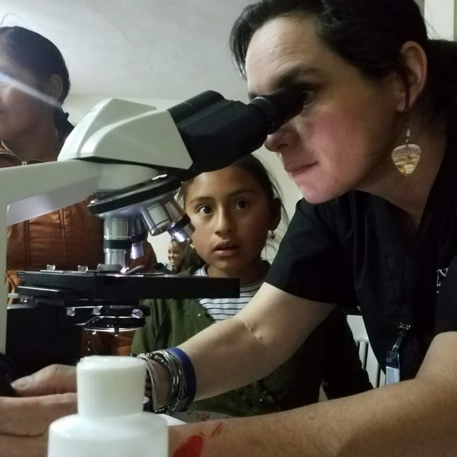 Professor showing a local Peruvian girl how to view a parasite under the microscope