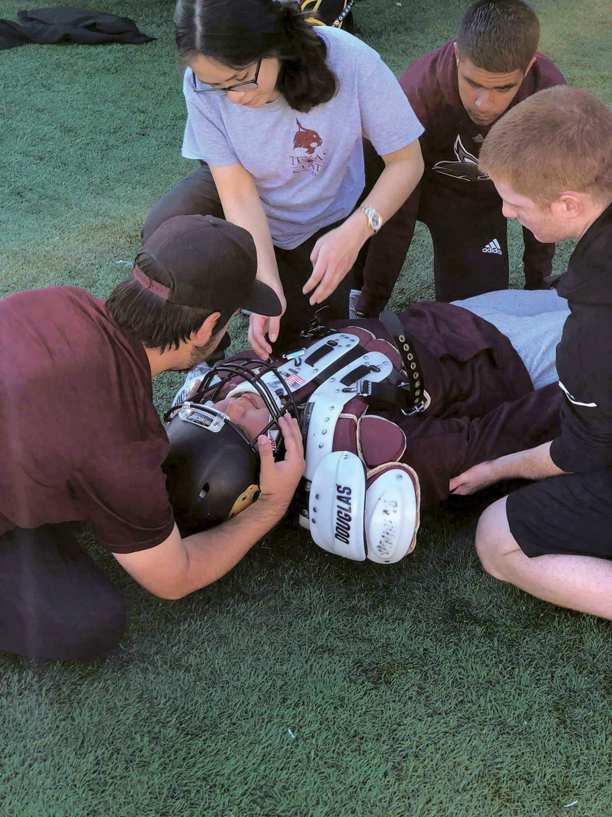 students looking over a football player on the ground