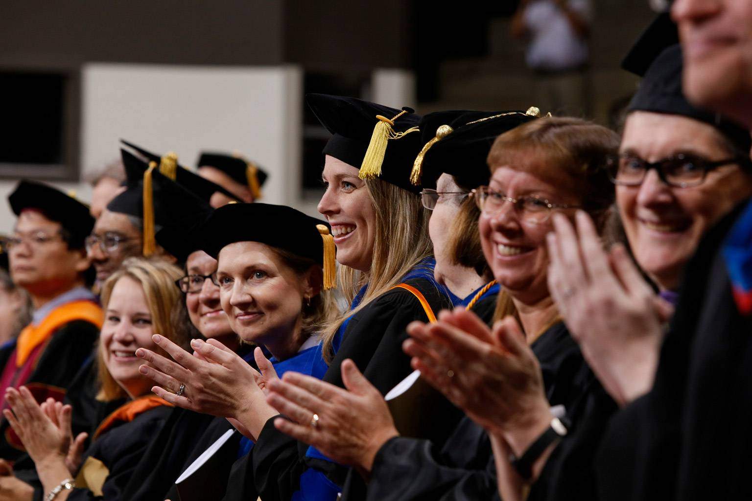 a row of faculty member clap during a commencement ceremony