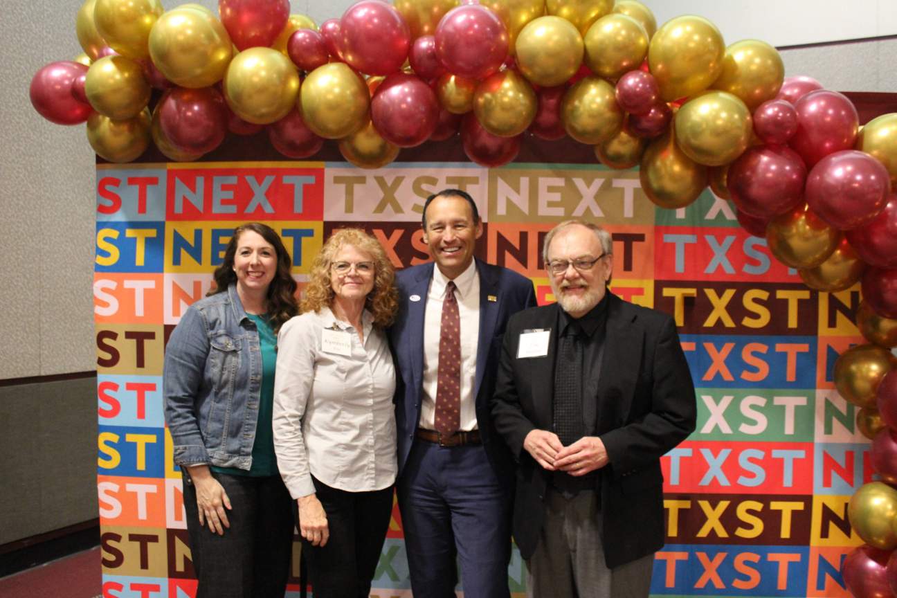 three TXST employees with President Damphousse