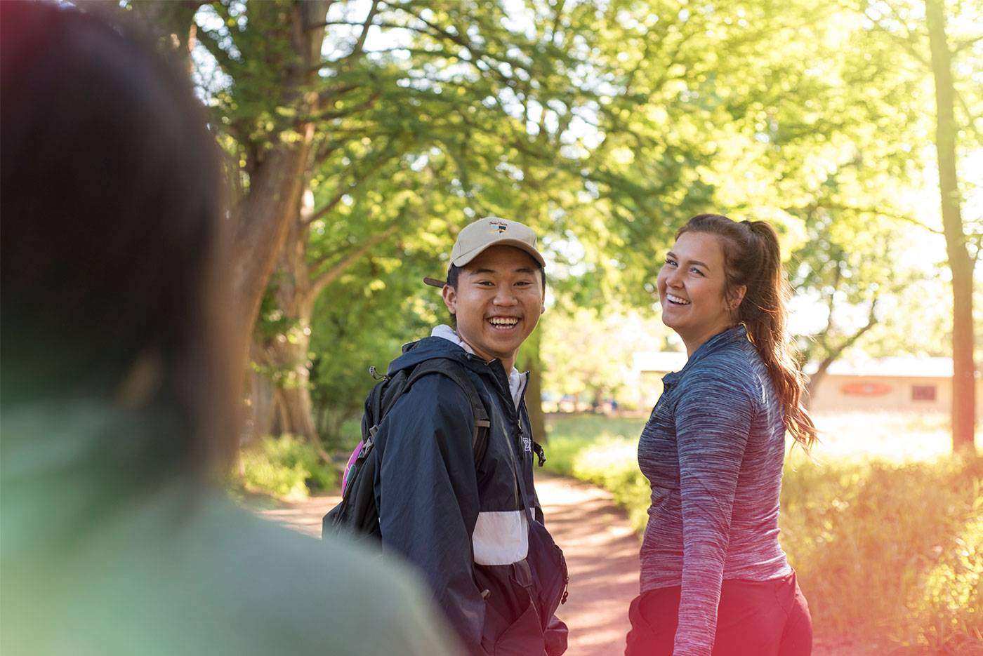 Students walking on a nature trail, smiling. 