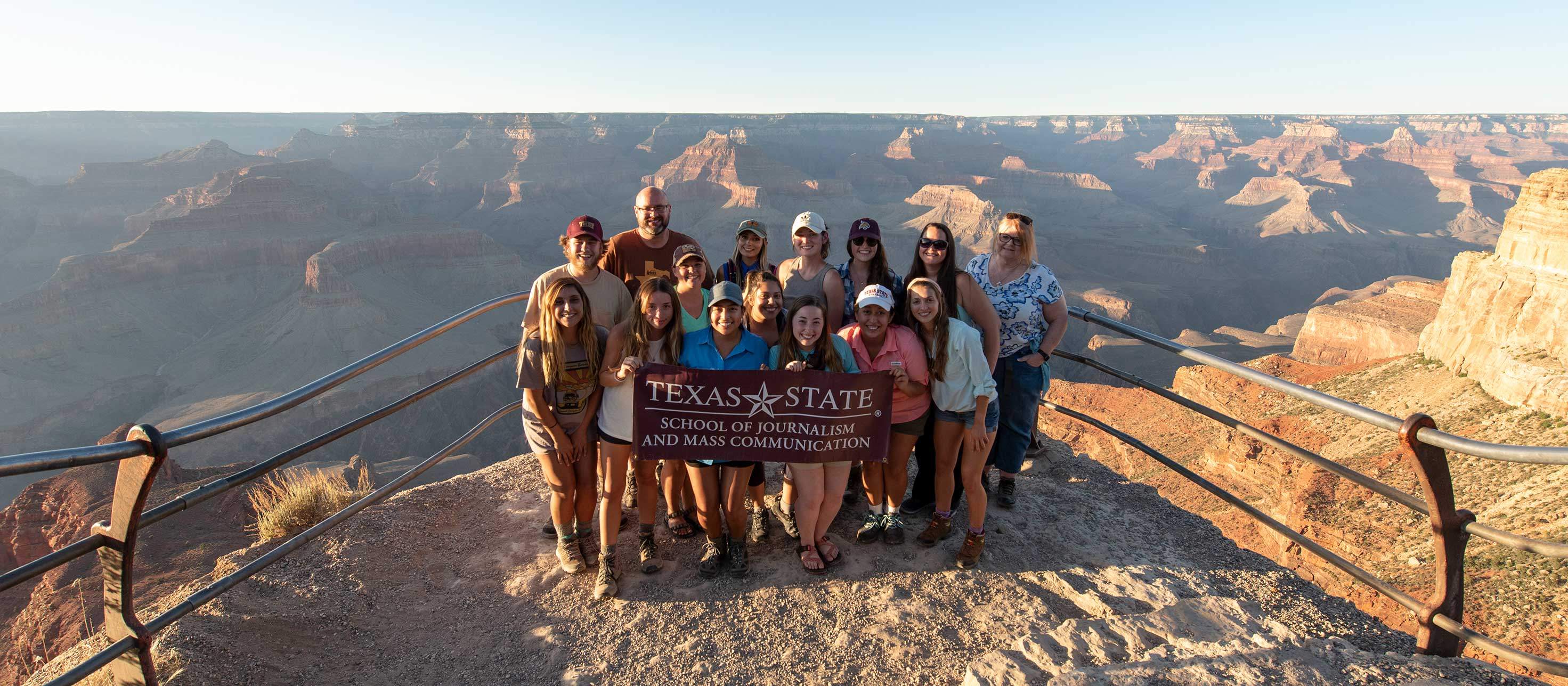 the mobile storytelling group takes a group photo in front of the grand canyon