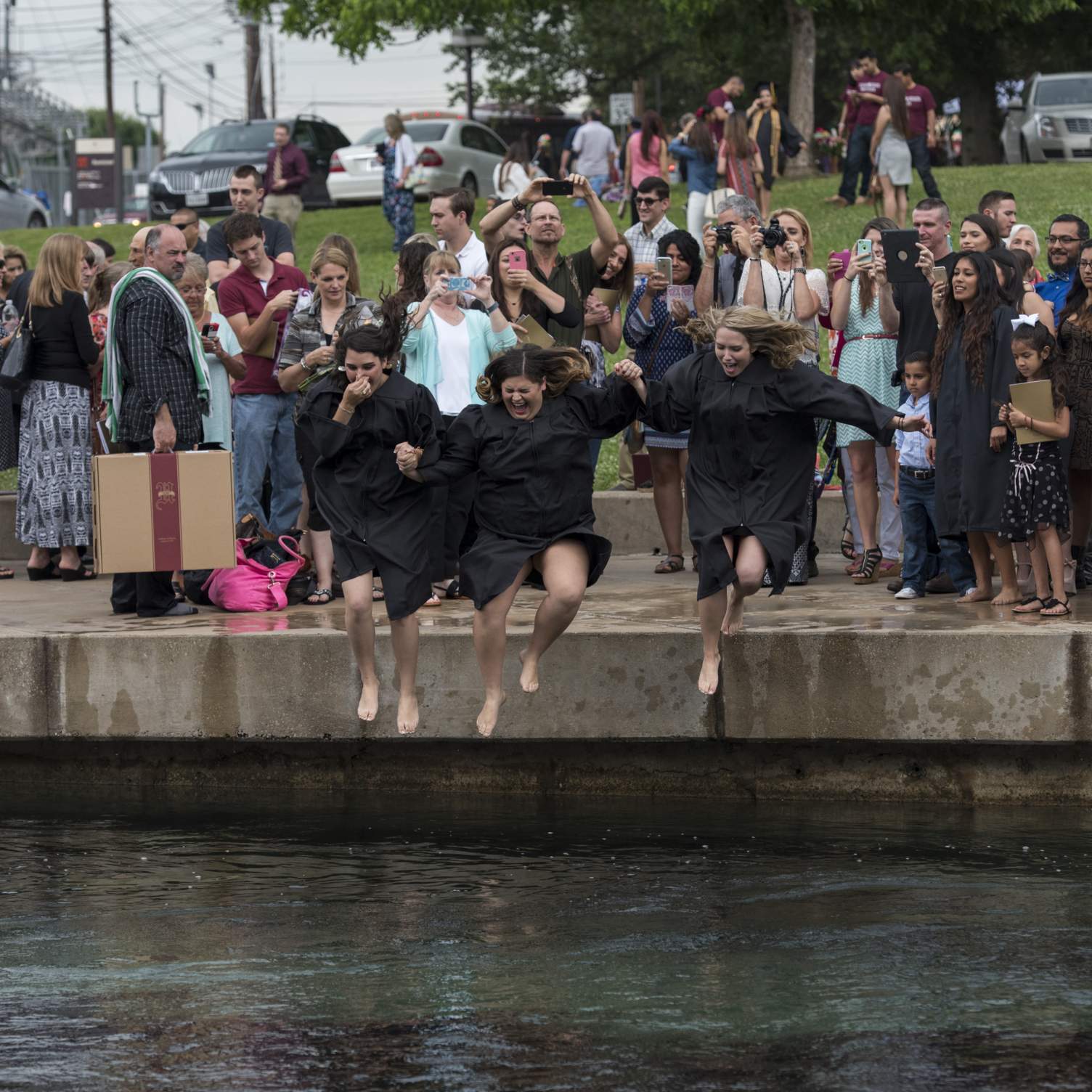 Three graduates jumping into the river