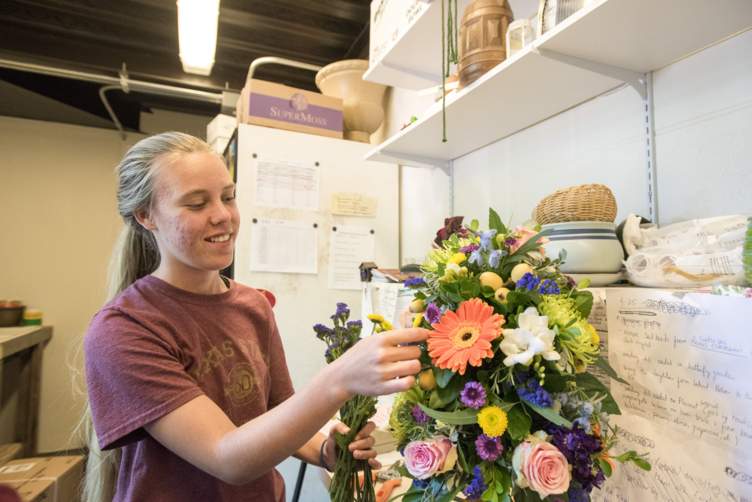 student in work room building a floral arrangment 