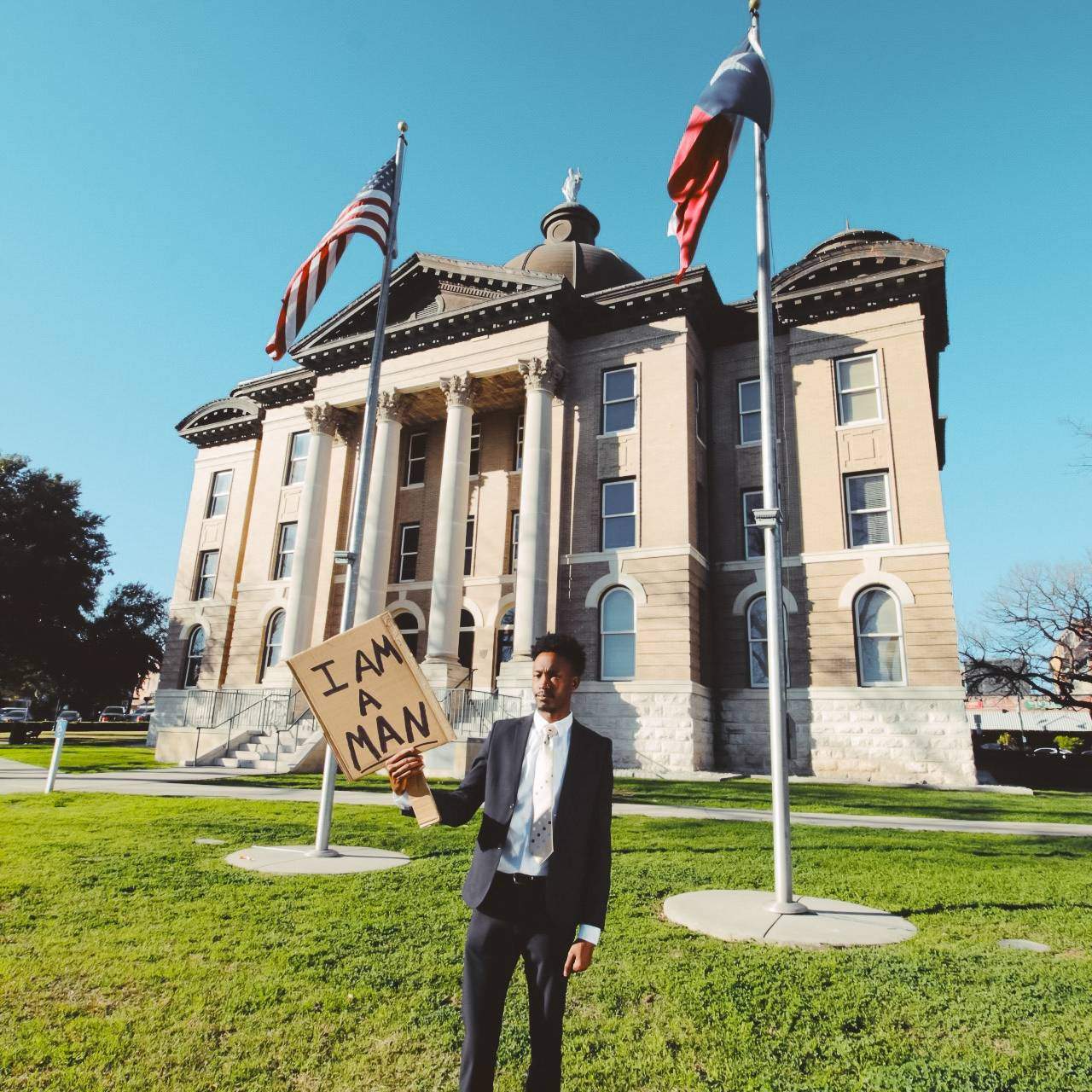 one person standing in front of court house with sign