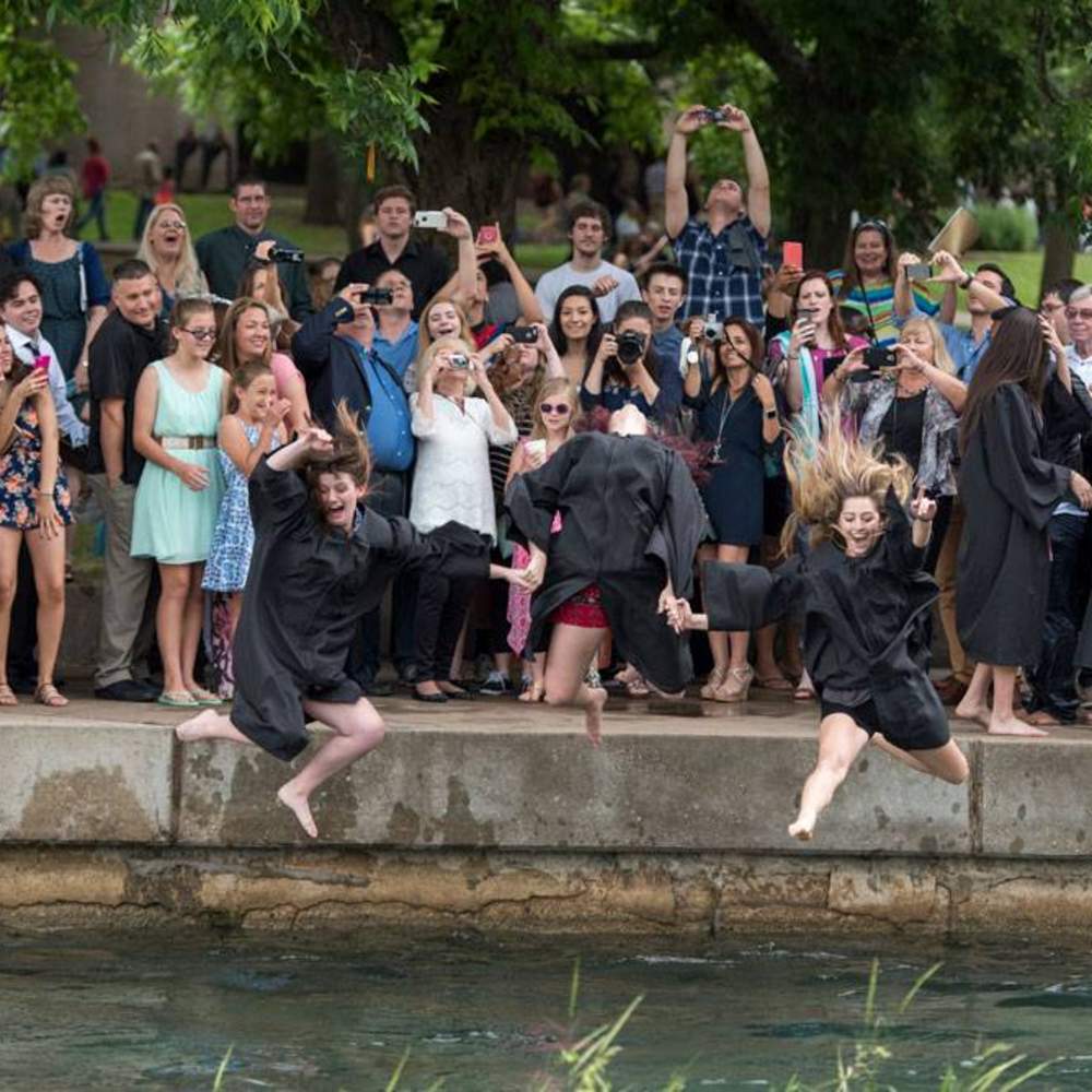 crowd cheering graduates as they jump into the river