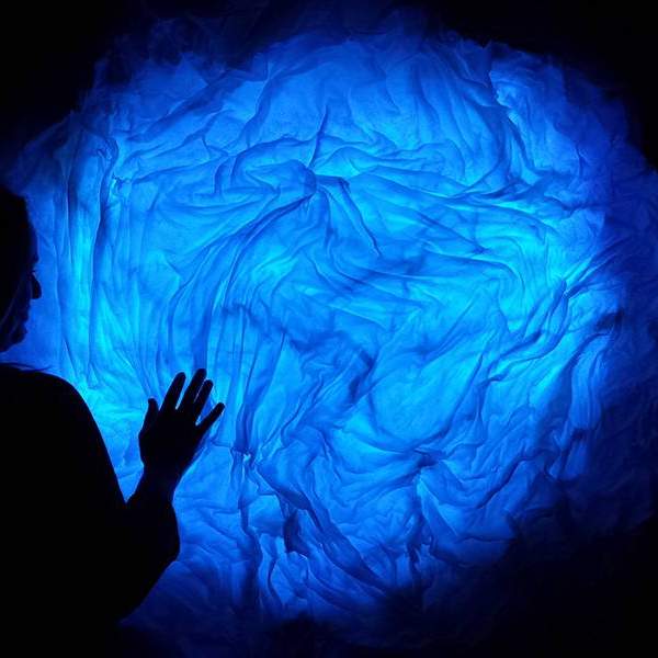 Student work: a blue fabric form glowing from within and a viewer silhouetted against it
