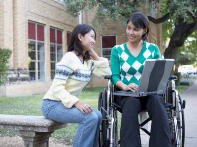 Female talking to female in wheel chair wih computer in her lap