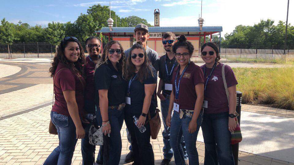 Student smiling in Texas State shirts outdoors