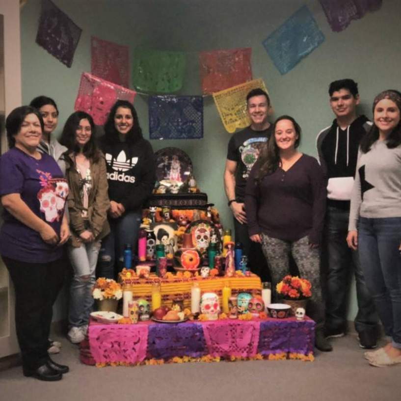 Several people standing around a Day of the Dead altar