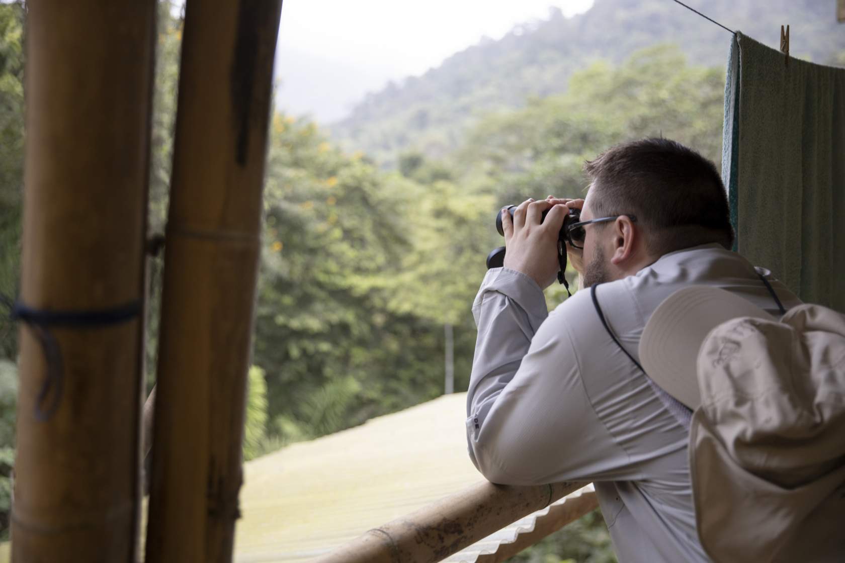 Austin Banks uses binoculars to look for birds in the rainforest
