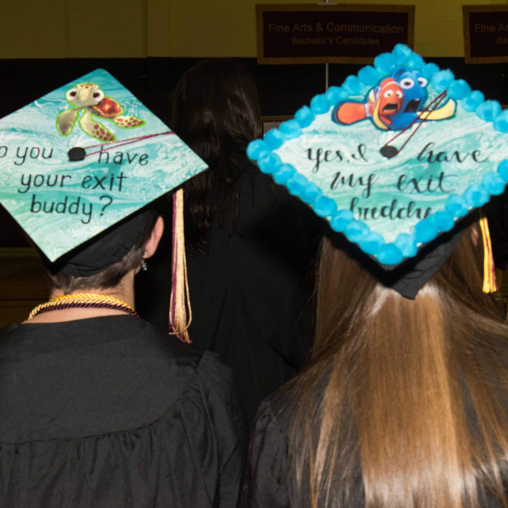 Cap design by graduates saying (cap one) "do you have your exit buddy?" and (cap two) "Yes, I have my exit buddy"