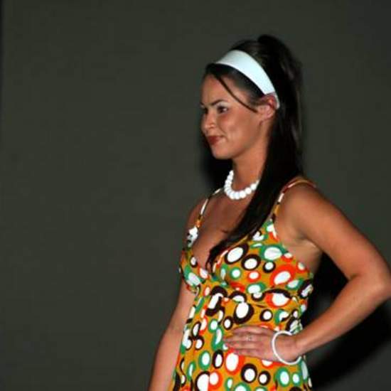 Close-up of student wearing bright colored circle print dress, white headband, and white bead necklace.