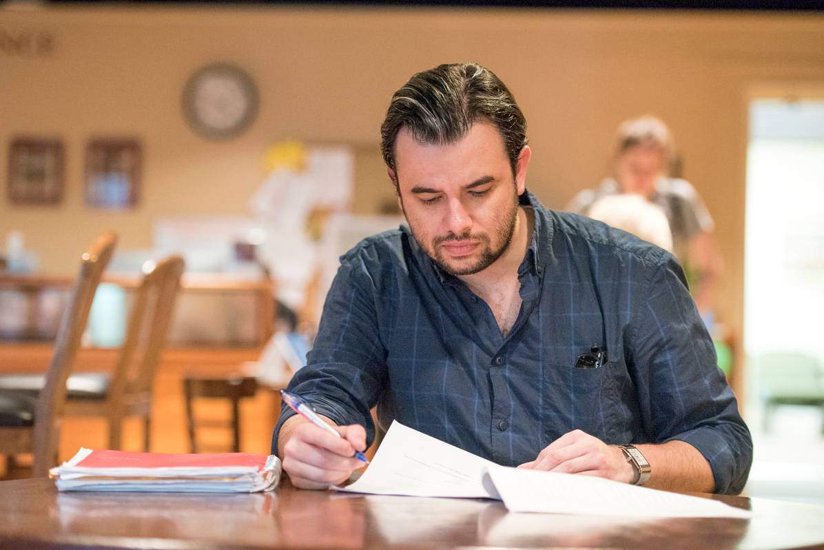 man sitting at table with papers studying