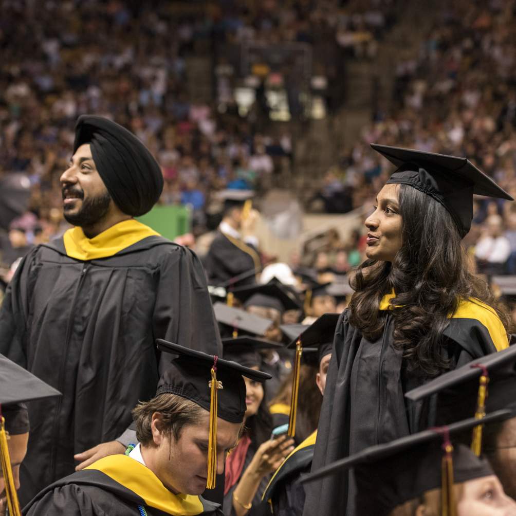 Masters of Science candidates, indicated by the gold color of their ceremonial hoods, search the crowd for family and friends during the Spring 2016 Commencement Ceremony.