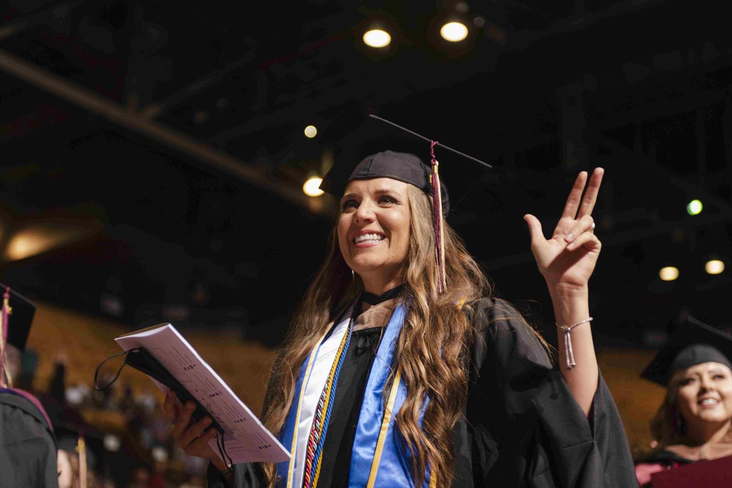 a student holds up the Texas State hand sign during a commencement ceremony