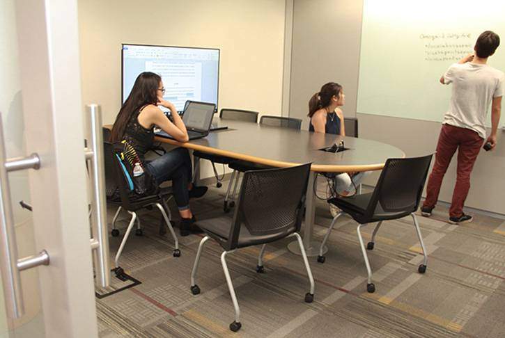 a collaboration room shows three students working on a project at the white board
