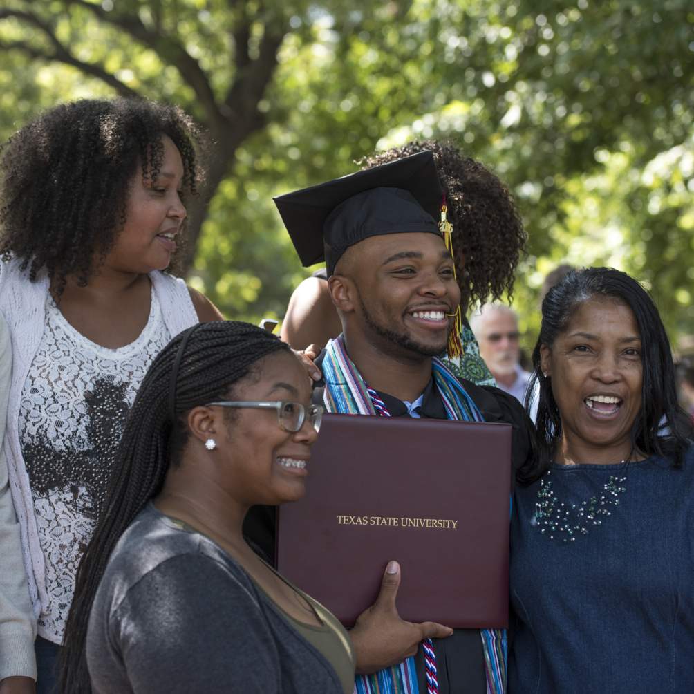 The family of a brand new graduate poses for photos on the lawn outside the University Events Center (formerly Strahan Coliseum) after a Summer 2016 commencement ceremony.