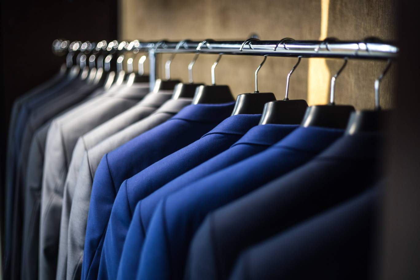 gray, blue and black suit jackets hanging on a clothes rack