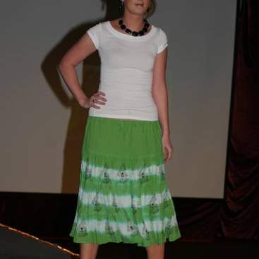 Student wearing green & white skirt, white shirt, black bead necklace and black high-heels.