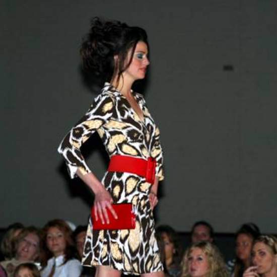 Student wearing an animal print dress, red beat and a red purse. 