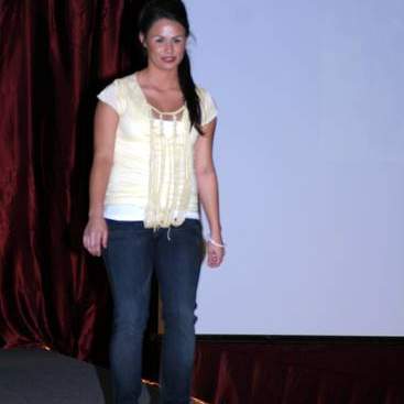 Student wearing yellow rag style top over a white shirt, jeans and white high-heels.