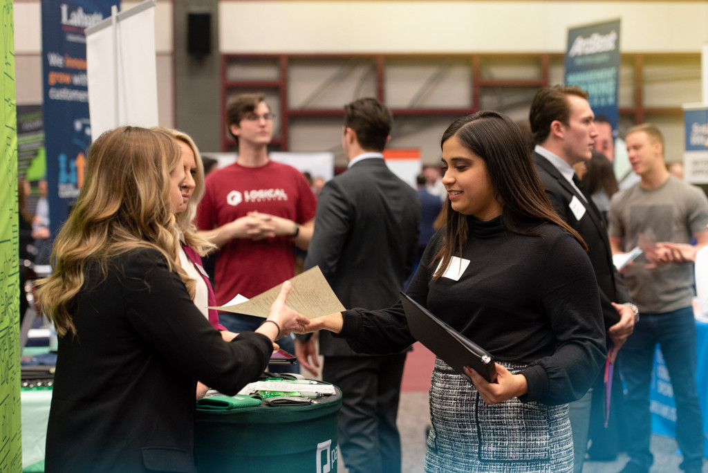 Student hands resume to recruiter at a Texas State career fair.