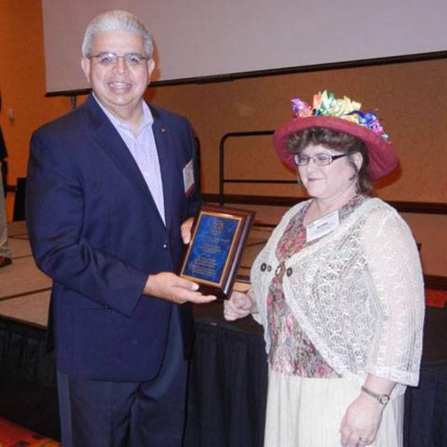 Kathy Pollock, Code Enforcement Officer and Assistant to the City Administrator for the City of Somerville Texas receives a plaque from TCMA President Burt Lumbreras recognizing him as a recipient of the Barney Knight TCMA Scholarship.