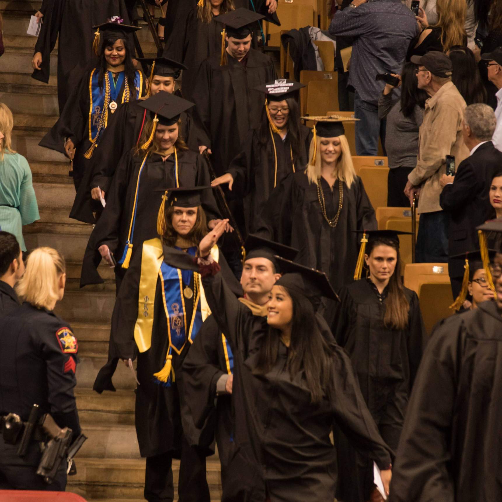 An enthused baccalaureate candidate waves to guest in the crowd