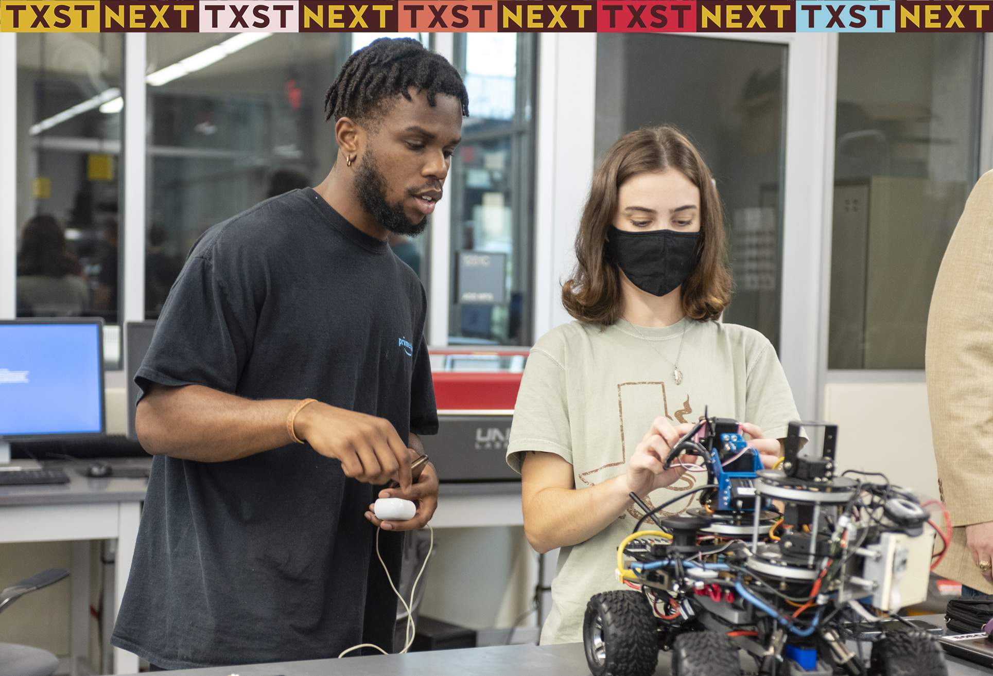 Two undergraduate students working with a robotic machine at a laboratory inside the Ingram School of Engineering.