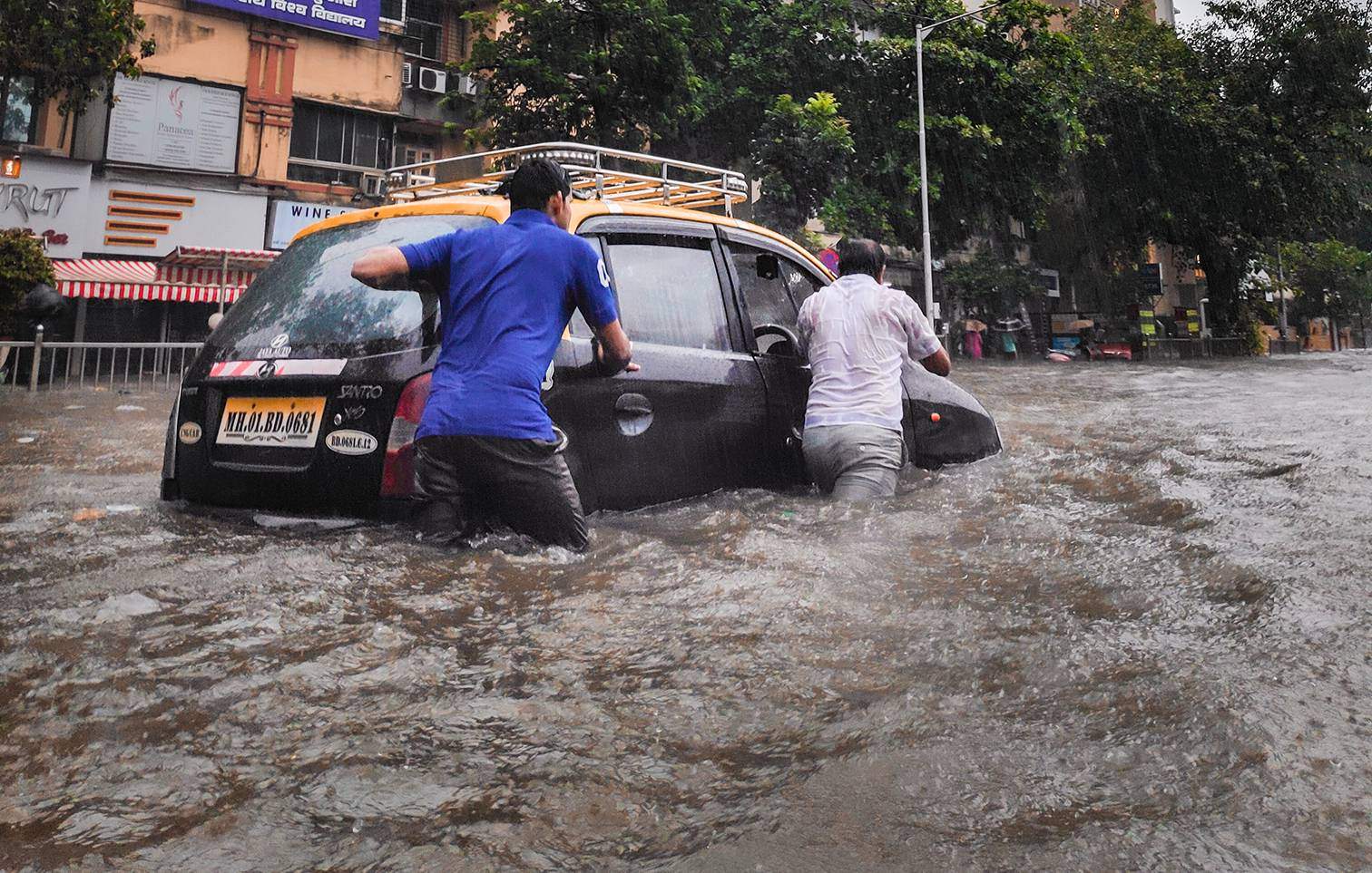 two people pushing car through flooded street