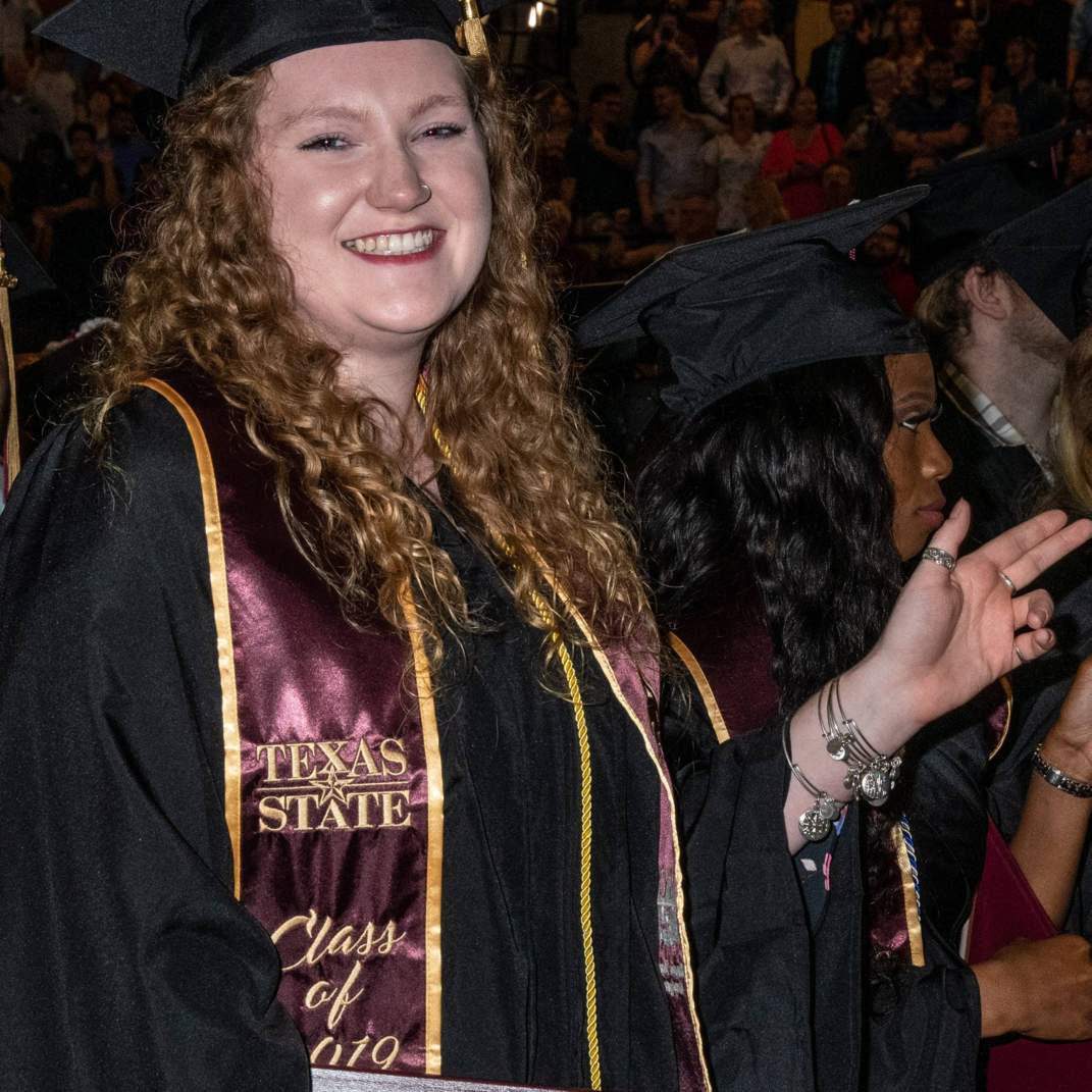 Graduate holding up the Texas State handsign