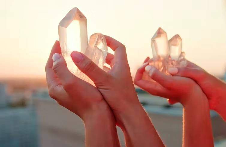 two people holding up clear quartz in sunlight