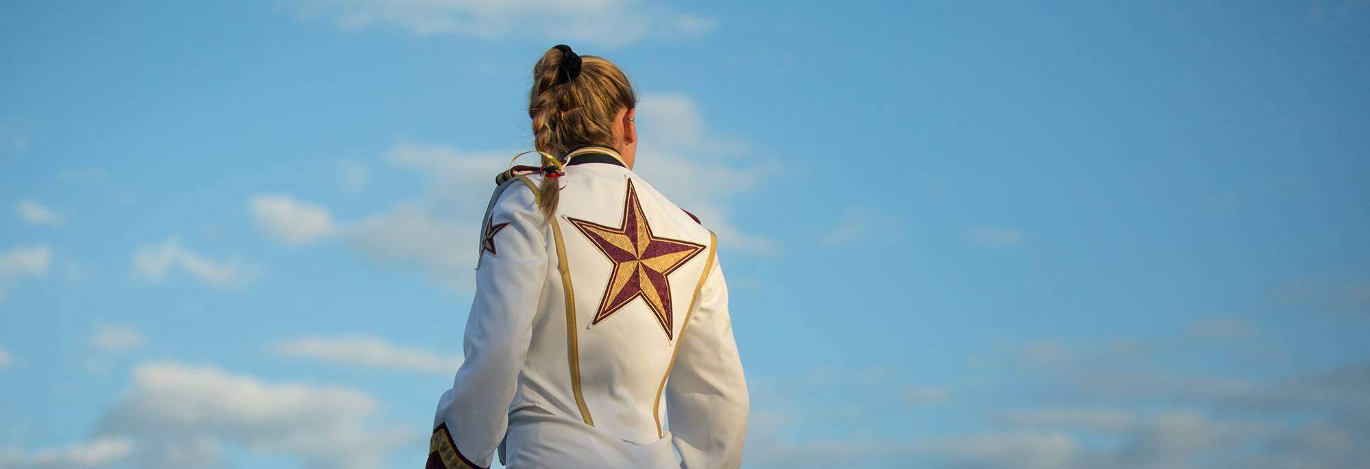 drum major Bethany Smith looks off into distance with blue sky in background