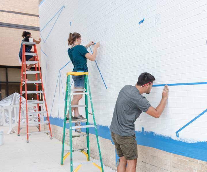 students taping txst mural