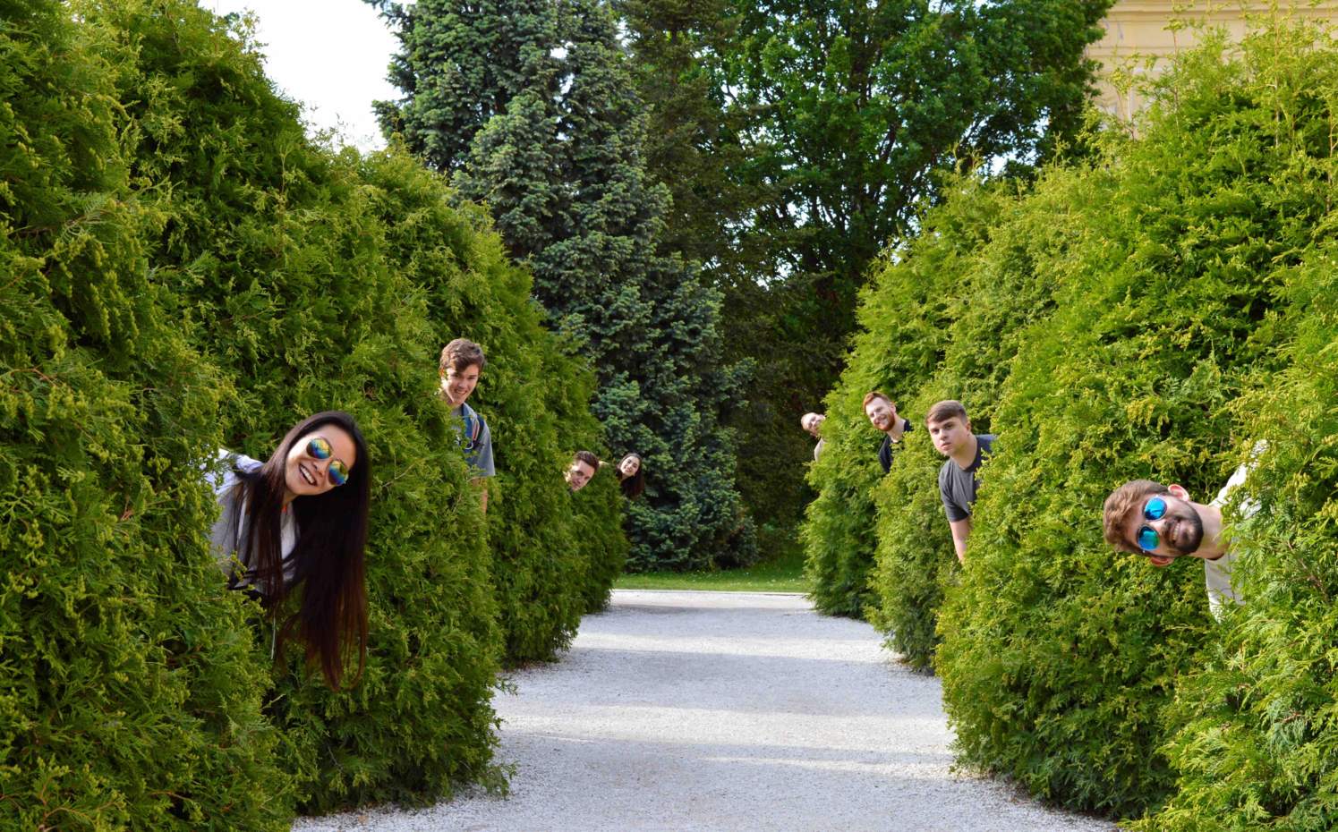 Students poking heads out from behind shrubs on study abroad trip