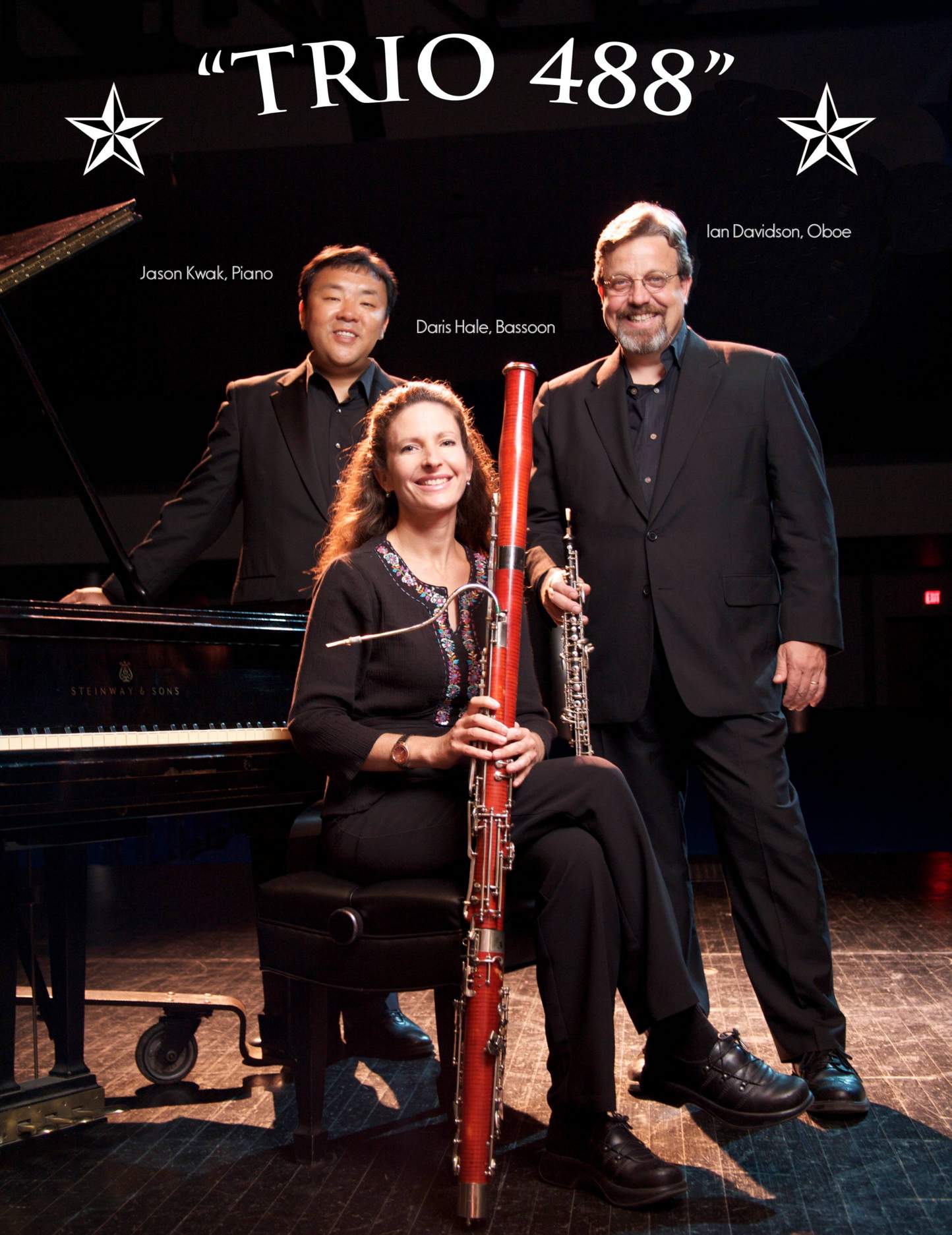 left to right, Jason Kwak next to piano, Daris Hale with bassoon, Ian Davidson with oboe with stage background
