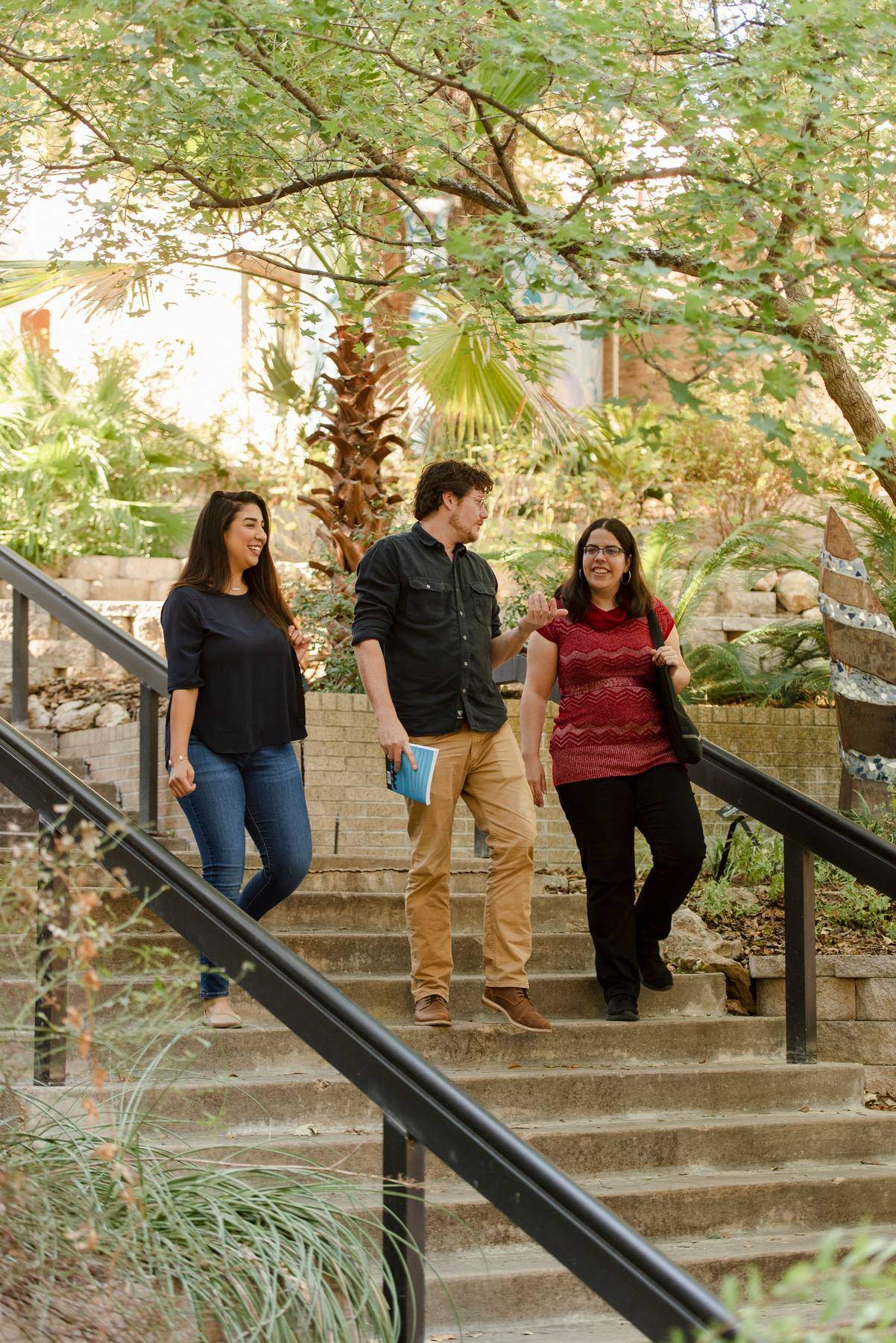 Three student walking down exterior campus stairs.