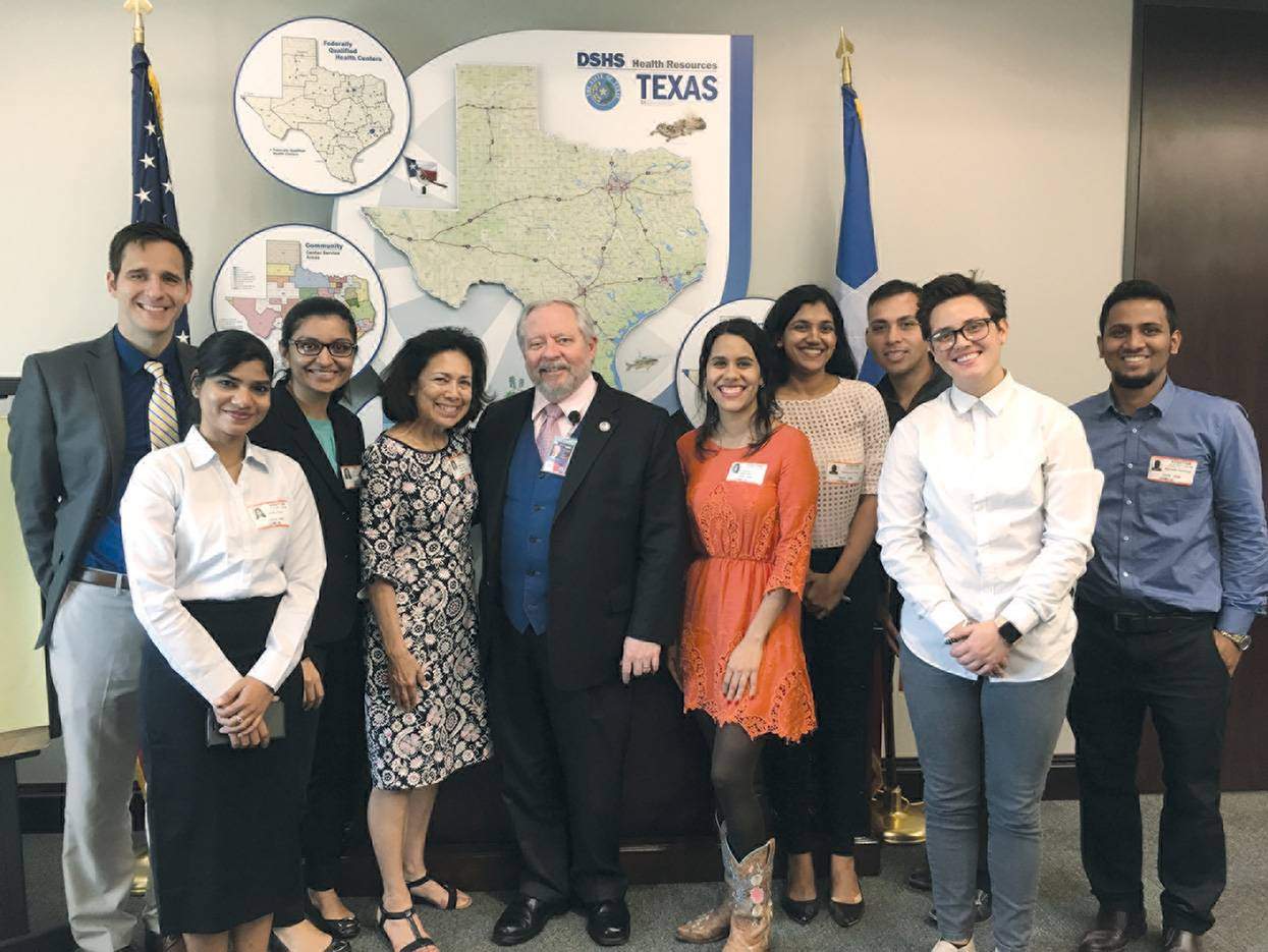 a group of people taking a group picture in front of a Texas presentation