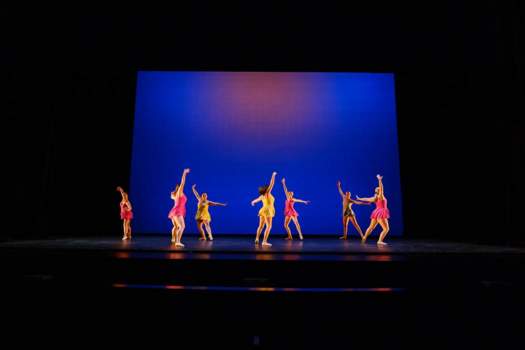 Dancers on stage in colorful costumes at Texas State University