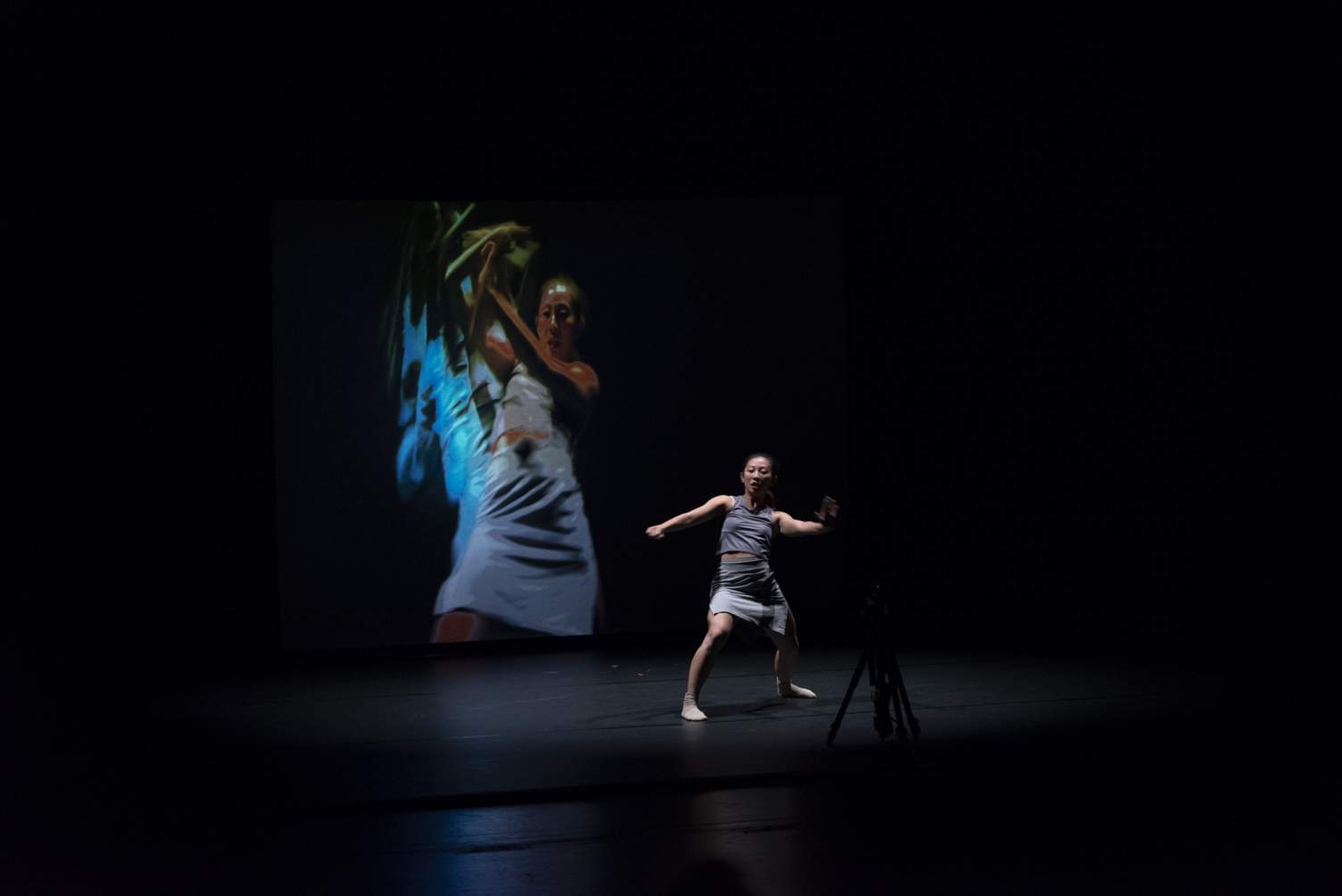 A dancer on stage using a camera to create projections at Texas State University
