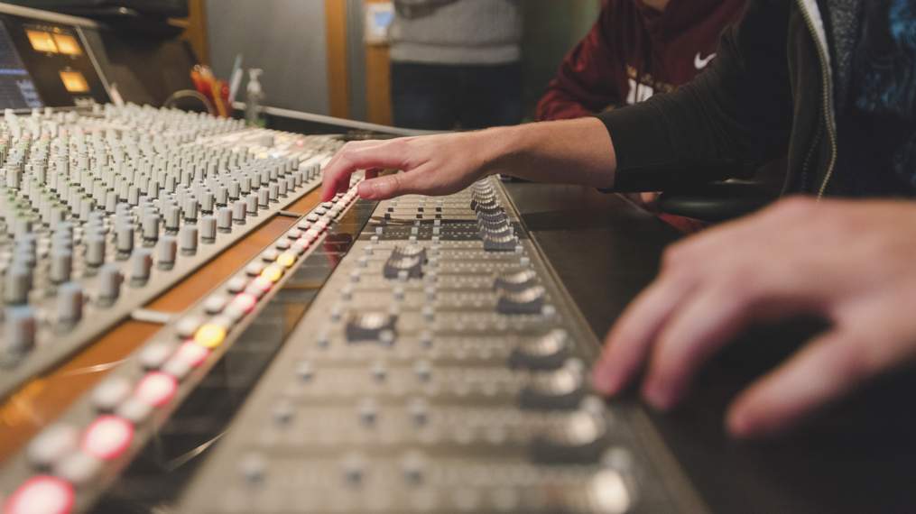 A zoomed shot of two hands working on a mixing board.