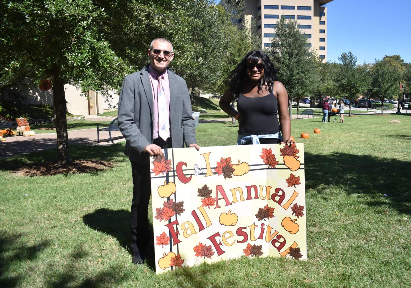 Dr. Polat and Kei holding an Annual Fall Festival sign