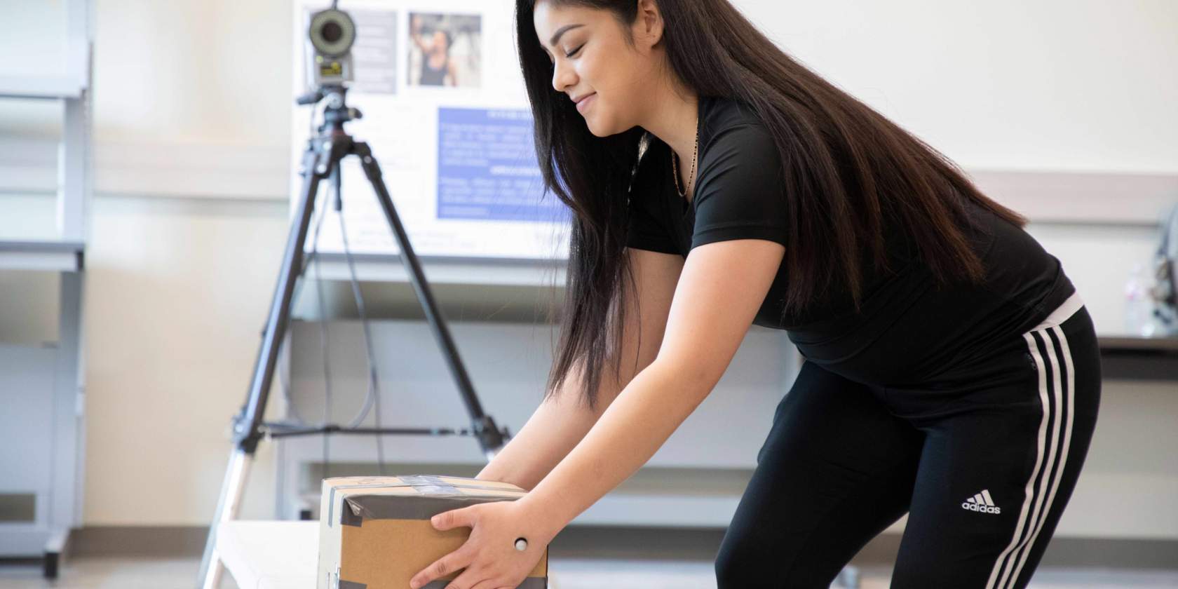 Student picking up a box with sensor on her hand