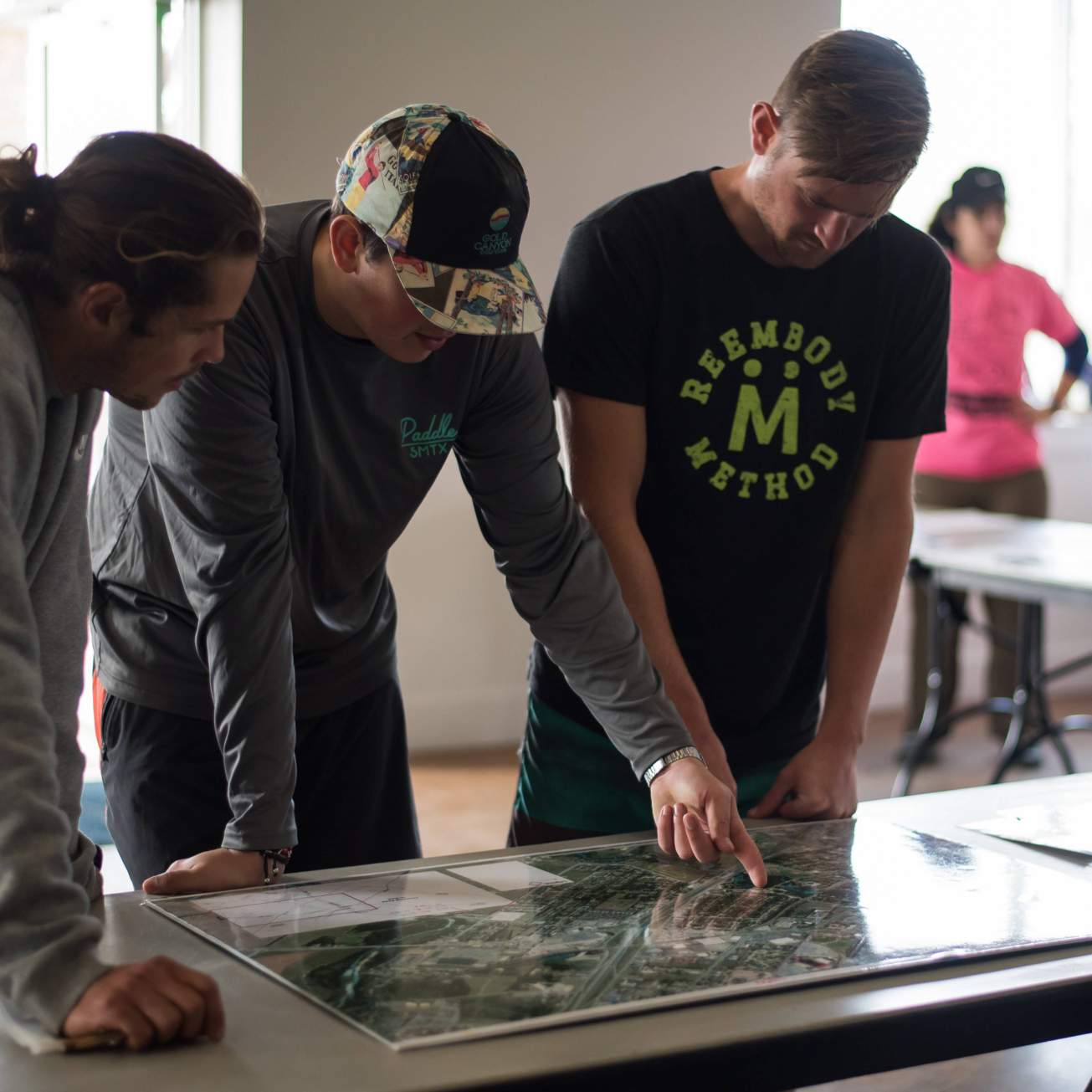 three San Marcos residents look at a map to plan out the river cleanup