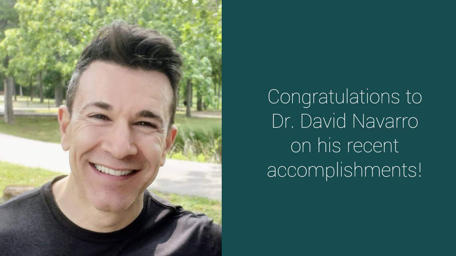 Man smiling, with trees, grass, sidewalk behind him. Text: Congratulations to Dr. David Navarro for his recent accomplishments!